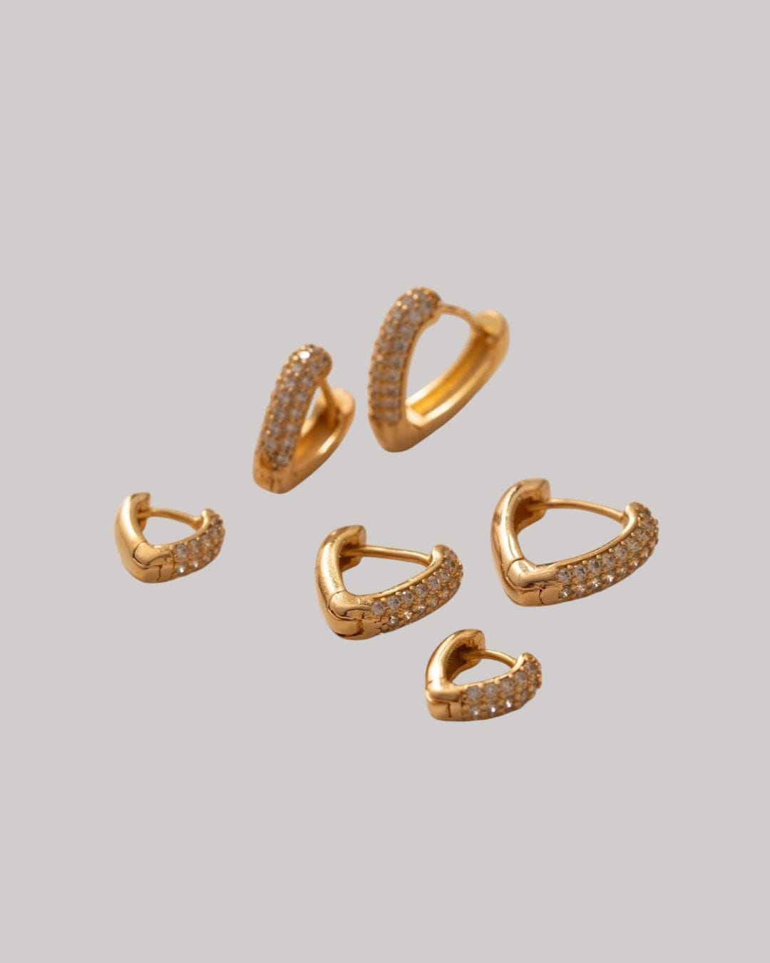 Golden Heart Trio Earrings | Golden Heart Trio Earrings Discover the stunning Golden Heart Trio Earrings – a radiant set of gold-plated heart-shaped hoops encrusted with shimmering crystals. Designed to reflect love, elegance, and style, these earrings are perfect for both everyday wear and special occasions. Crafted with hypoallergenic materials, free from nickel, lead, and cadmium, they’re safe for sensitive skin and ideal for women who appreciate luxurious, romantic, and timeless jewelry. Shop now at Madu Joia Rara to add sparkle and sophistication to your collection.