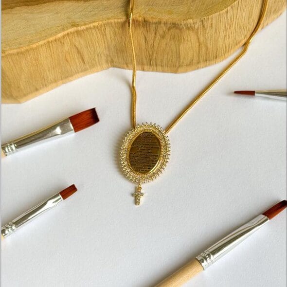 Golden Prayer Pendant Necklace featuring 18k gold-plated oval pendant with engraved prayer, pavé zirconia border, and cross charm