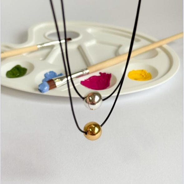 Golden & Silver Sphere Pendant Necklace featuring two polished spheres on a black cord with 18k gold plating