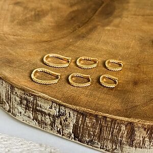 Trio Stud Earrings Set Three pairs of minimalist stud earrings in 18K gold-plated finish displayed on a rustic wooden board with a natural bark edge.