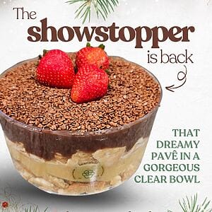 Close-up of Karamelado’s Double Brigadeiro Pavê in a transparent bowl, highlighting the layers of creamy white brigadeiro, rich chocolate brigadeiro, and biscuit pieces. The top is covered with chocolate sprinkles and garnished with fresh strawberries, creating a festive and indulgent look.