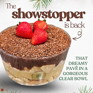 Close-up of Karamelado’s Double Brigadeiro Pavê in a transparent bowl, highlighting the layers of creamy white brigadeiro, rich chocolate brigadeiro, and biscuit pieces. The top is covered with chocolate sprinkles and garnished with fresh strawberries, creating a festive and indulgent look.