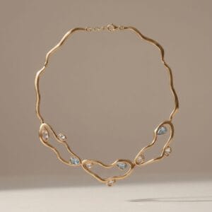 Gold diamond-style necklace with high-shine stones displayed on a soft neutral background, a luxurious Mother’s Day gift by Madu Joia Rara.