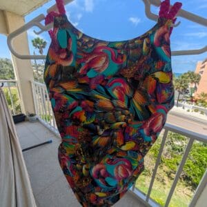 Colorful tropical bird print one‑piece swimsuit with braided pink straps, Fashion Brasil Sun and Sea.