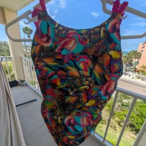 Colorful tropical bird print one‑piece swimsuit with braided pink straps, Fashion Brasil Sun and Sea.