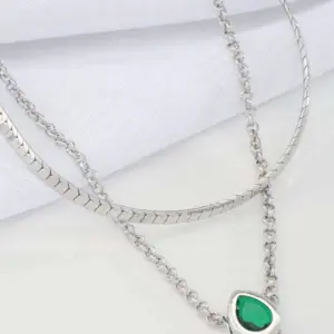 Modern double layer silver necklace with green gemstone-style pendant displayed on a light background