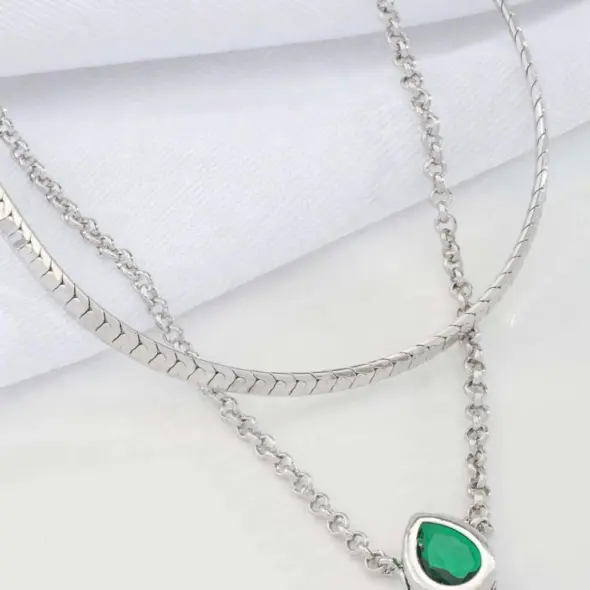 Modern double layer silver necklace with green gemstone-style pendant displayed on a light background