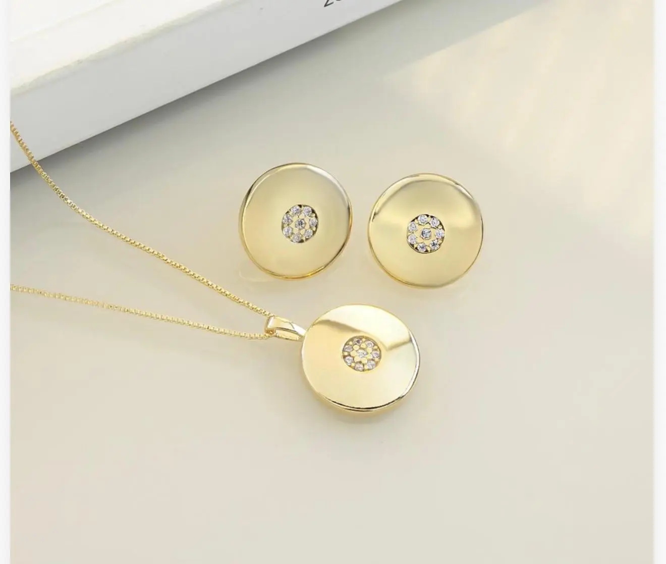 mari semijoias gold plated jewelry set lifestyle | Golden Radiance Jewelry Set - Mari Semijoias Mari Semijoias circular pendant necklace and stud earrings featuring elegant zirconia accents Photo 3