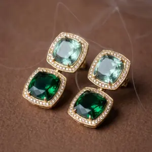 Gold-tone drop earrings featuring emerald green and soft green faceted stones framed by sparkling zirconia halos, creating a sophisticated geometric design by Madu Joia Rara.