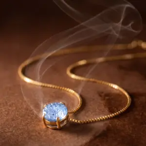 Delicate gold-tone necklace featuring a round SKY blue lab-reconstituted natural stone in a classic four-prong setting, suspended from a fine chain and displayed on a luxurious warm background by Madu Joia Rara.
